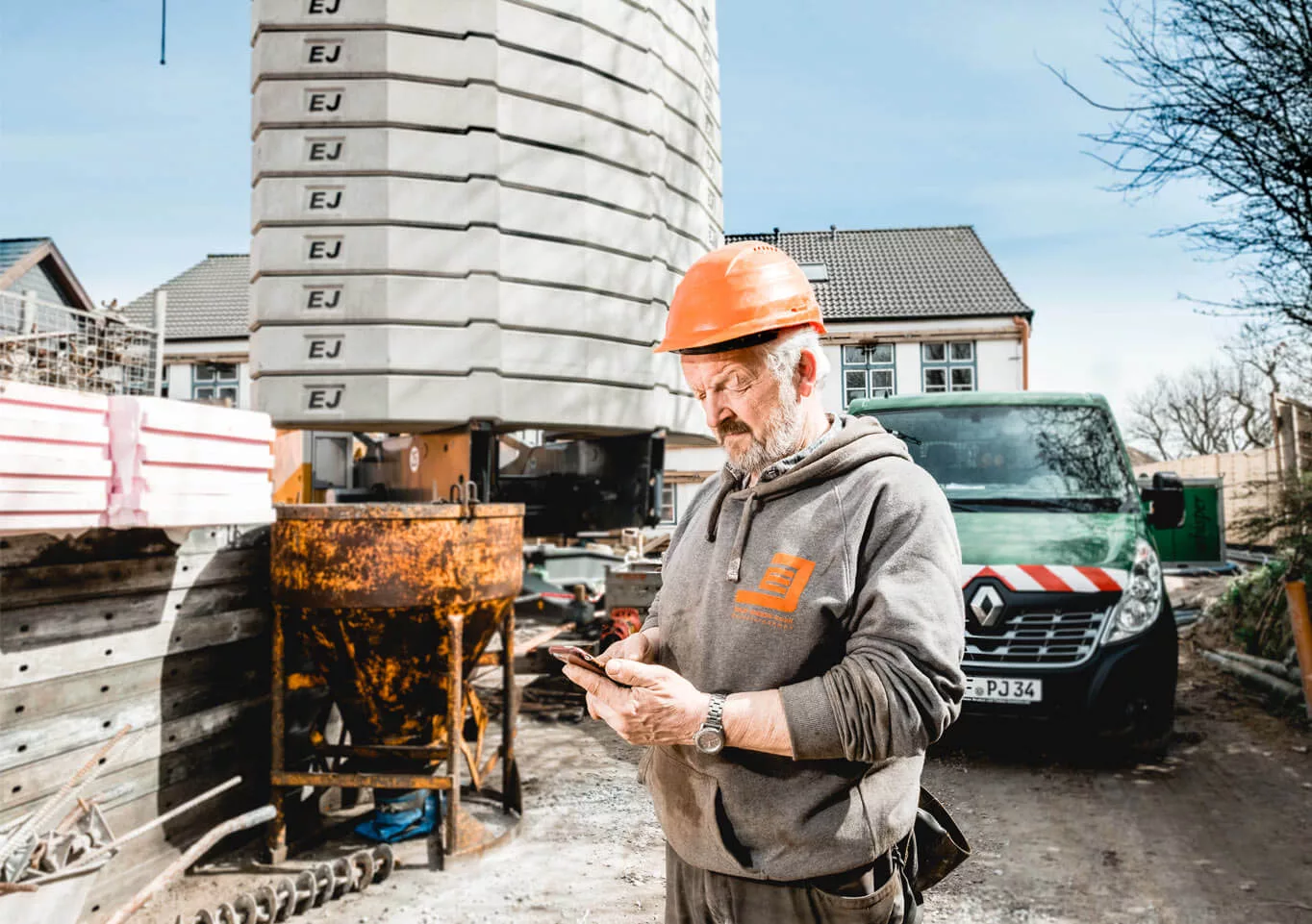 Geschäftsführer der Edlef Jensen GmbH schaut auf der Baustelle auf sein Handy